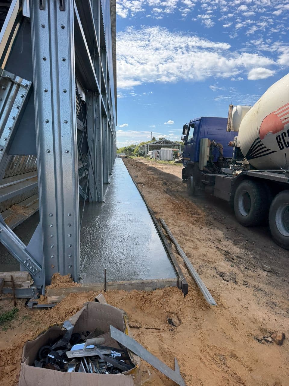 Бетонная отмостка по периметру ангара после укладки и затирки, опалубка держит внешний край ленты
